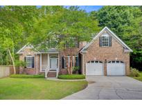 Charming brick home with a well-manicured lawn, mature tree, and attached two-car garage at 1851 Oleander Ct, Charleston, SC 29414