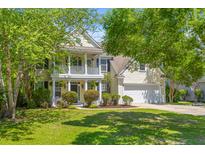 Charming two-story home boasts a welcoming front porch and a well-manicured lawn with mature trees at 2184 Tall Grass Cir, Mount Pleasant, SC 29466