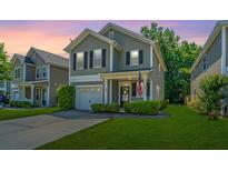 Charming two-story home featuring manicured lawn, gray siding and an inviting front porch with a US flag at 286 Chemistry Cir, Ladson, SC 29456