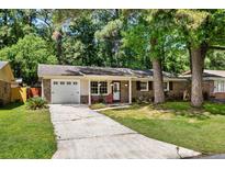 Quaint brick home with well-kept lawn, a driveway, and a welcoming entrance with chairs at 315 Elliott Dr, Ladson, SC 29456