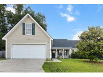 Inviting tan home with a spacious two-car garage, green shutters, and a well-manicured front yard at 402 Equinox Cir, Ladson, SC 29456