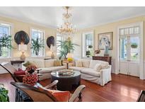 Bright living room featuring a chandelier, white sofa, wood floors, and large windows at 5 Legare St # C, Charleston, SC 29401