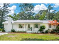 Charming single-story home featuring white brick, a brick chimney, and a lush green lawn at 521 Carpenter St, Charleston, SC 29412