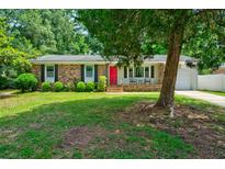 Charming brick home with a red door, lush green lawn, and mature trees at 7 Azalea Ct, Goose Creek, SC 29445