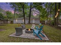 Charming backyard with a fire pit, Adirondack chairs, and well-maintained lawn offers an ideal spot for outdoor relaxation at 825 Savage Rd, Charleston, SC 29414