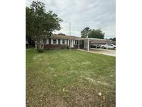 Traditional brick home featuring a well-manicured lawn and convenient covered parking at 8612 Delhi Rd, North Charleston, SC 29406