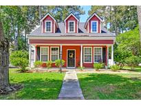 Charming two-story red home featuring a well-manicured lawn and inviting front porch at 8965 N Red Maple Cir, Summerville, SC 29485