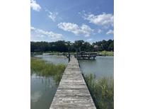 Scenic waterfront view showcasing a private wooden dock and pier with a charming seating area under a cloudy sky at 932 N Shem Dr, Mount Pleasant, SC 29464