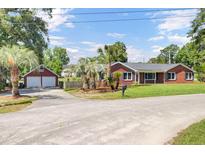Charming brick home with mature palm trees and a two-car garage at 1027 E Recess Rd, Hanahan, SC 29410