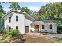 Charming painted brick home featuring a beautiful wood front door and attached garage surrounded by mature trees at 1055 Royalist Rd, Mount Pleasant, SC 29464