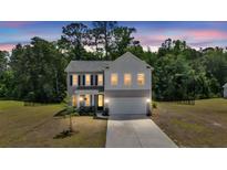 Charming two-story home featuring a two-car garage, black shutters, and a manicured front lawn at 1132 Wading Point Blvd, Huger, SC 29450