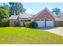 Charming brick home featuring a two-car garage, lush lawn, and solar panels for energy efficiency at 1287 Chatfield St, Mount Pleasant, SC 29464