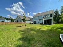 Spacious backyard featuring lush lawn, wooden fence, and a screened-in porch, perfect for outdoor enjoyment at 141 Cherry Grove Dr, Summerville, SC 29483