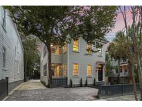 Charming two-story home featuring gray siding, black trim, brick driveway, and a cozy screened porch on the second level at 19 Smith St # B, Charleston, SC 29401