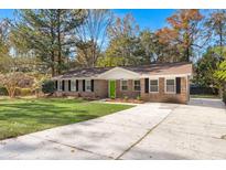 Charming brick home featuring a lush green lawn, a long concrete driveway, and vibrant green front door at 205 Owens Dr, Summerville, SC 29485