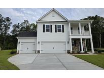 Charming two-story home with a three-car garage, white siding, and a cozy front porch at 251 Darby Meadow Ln, Ridgeville, SC 29472