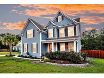 Charming two-story home with blue siding and a manicured front yard set against a colorful sunset sky at 5525 Alpine Dr, Summerville, SC 29483
