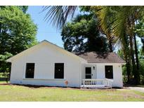 Charming white home featuring black-trim windows, lovely landscaping, and a welcoming front entrance at 7774 Ginger Ln, North Charleston, SC 29420