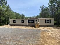 New manufactured home with tan and grey siding, black shutters, wood porch steps, and gravel in the front yard at 852 Lawyer Ln, Cross, SC 29436