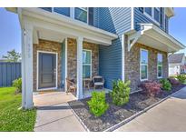Charming front porch with stone accents, seating, and landscaped garden bed, exuding curb appeal at 175 Darby Meadow Ln, Ridgeville, SC 29472