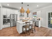 Bright kitchen with white cabinets, wood floors, stainless steel appliances, and pendant lighting at 200 Bear Oak Ct, Moncks Corner, SC 29461