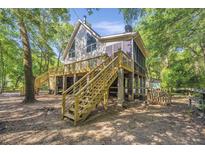 A charming coastal home featuring a spacious elevated deck, screened in porch, and a natural wooded setting at 2468 Marina Rd, Wadmalaw Island, SC 29487