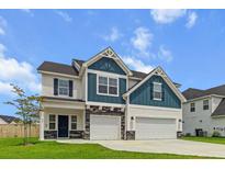 Charming two-story home with a manicured lawn, three car garage, and attractive blue and white color scheme at 277 Fiddleback Dr, Summerville, SC 29486