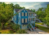 Charming two-story blue home featuring a double porch, lush landscaping, and a garage at 3711 Tip Ln, Mount Pleasant, SC 29466