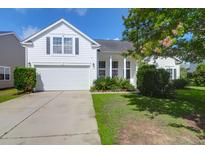 Charming white home with a well-manicured lawn, attached garage, and lovely landscaping at 7302 Sanderling Ct, Hanahan, SC 29410