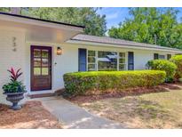 Charming white brick home with a well-manicured lawn and a dark wooden front door with glass panels at 734 Fort Sumter Dr, Charleston, SC 29412