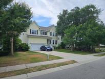 Charming two-story home with a well-manicured lawn, attached garage, and a blue car parked in the driveway at 1495 Keshi Pearl Dr, Mount Pleasant, SC 29466