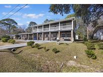 Two-story brick home featuring double balconies, a well-manicured lawn, and mature trees in a residential neighborhood at 1520 Acacia St, Charleston, SC 29407