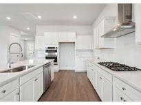 Bright kitchen features white cabinets, stainless steel appliances, a large island with sink, and hardwood floors at 211 Yalton St, Summerville, SC 29486