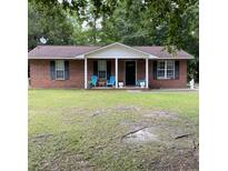Charming brick home featuring a cozy front porch with inviting blue chairs and manicured green lawn at 214 Winter St, Moncks Corner, SC 29461