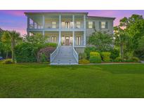 Stunning two-story home with double porches, lush landscaping, and a vibrant green lawn at 2269 Hartfords Bluff Cir, Mount Pleasant, SC 29466