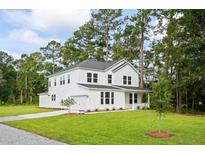 Charming two-story white home featuring a welcoming front porch, well-manicured lawn, and a gray shingle roof at 5180 Stono Plantation Dr, Hollywood, SC 29449