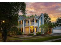 Charming two-story home with a double porch and manicured landscaping at sunset at 2900 Split Hickory Ct, Johns Island, SC 29455