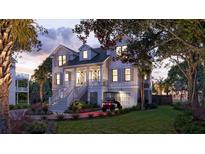 Stunning two-story home with inviting front porch, well-lit facade, and lush landscaping at dusk at 3307 Waterway Blvd, Isle of Palms, SC 29451