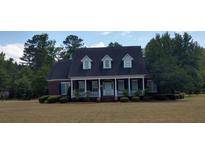 Charming brick home featuring a covered porch, manicured lawn, and classic architectural details at 351 Duncan Chapel Rd, Harleyville, SC 29448