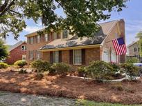 Charming two-story brick home with an American flag, manicured landscaping, and a welcoming front facade at 7 Lavington Rd, Charleston, SC 29407