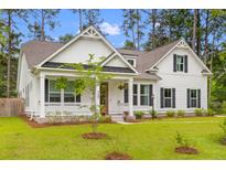 Charming two-story home featuring a inviting front porch, manicured lawn and attractive landscaping at 727 Hodge Rd, Summerville, SC 29483