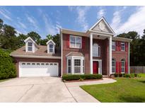 Charming two-story brick home featuring a two-car garage, red shutters, and beautiful landscaping at 8522 Long Meadow Dr, Charleston, SC 29420