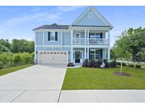Charming two-story home featuring a light blue facade, inviting front porch, and well-manicured lawn at 1004 Saltwater Cir, Johns Island, SC 29455