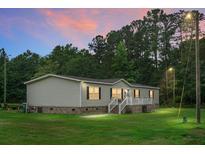 Charming single-story home with vinyl siding, a brick foundation, and a welcoming front porch under a colorful dusk sky at 1051 Cooper Store Rd, Moncks Corner, SC 29461
