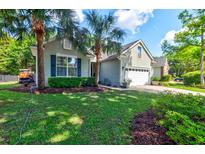 Charming single-story home with a well-manicured lawn, palm trees, and an attached two-car garage at 1231 Wild Olive Dr, Mount Pleasant, SC 29464
