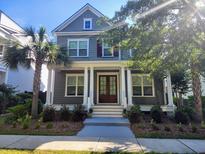 Charming two-story home with gray siding, white columns, front porch, landscaped yard, and mature palm trees at 1363 Rivella Dr, Mount Pleasant, SC 29464