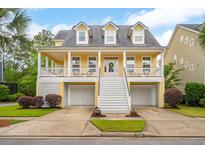 Charming yellow two-story home featuring a welcoming front porch and ground level two-car garage at 2267 N Marsh Dr, Mount Pleasant, SC 29466