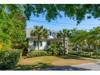 Charming two-story home with a cozy front porch, lush palm trees, and beautiful landscaping at 301 Center St, Mount Pleasant, SC 29464