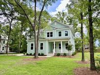 Charming two-story home with a welcoming front porch and a manicured lawn surrounded by mature trees at 5702 Barbary Coast Rd, Hollywood, SC 29449