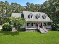 Charming home featuring a lovely front porch with an American flag and spacious lawn at 820 Old Cordesville Rd, Moncks Corner, SC 29461